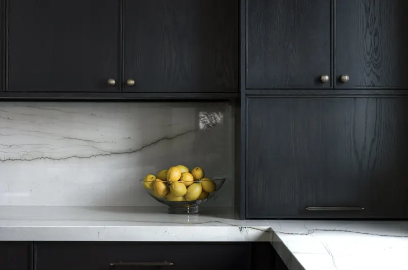 Matte black cabinetry with a book-matched stone backsplash